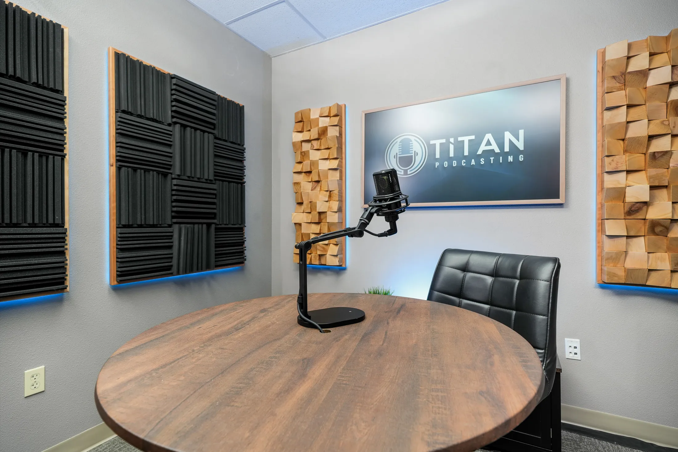 Prepared Titan Podcasting table, microphone, chair, and branded studio screen