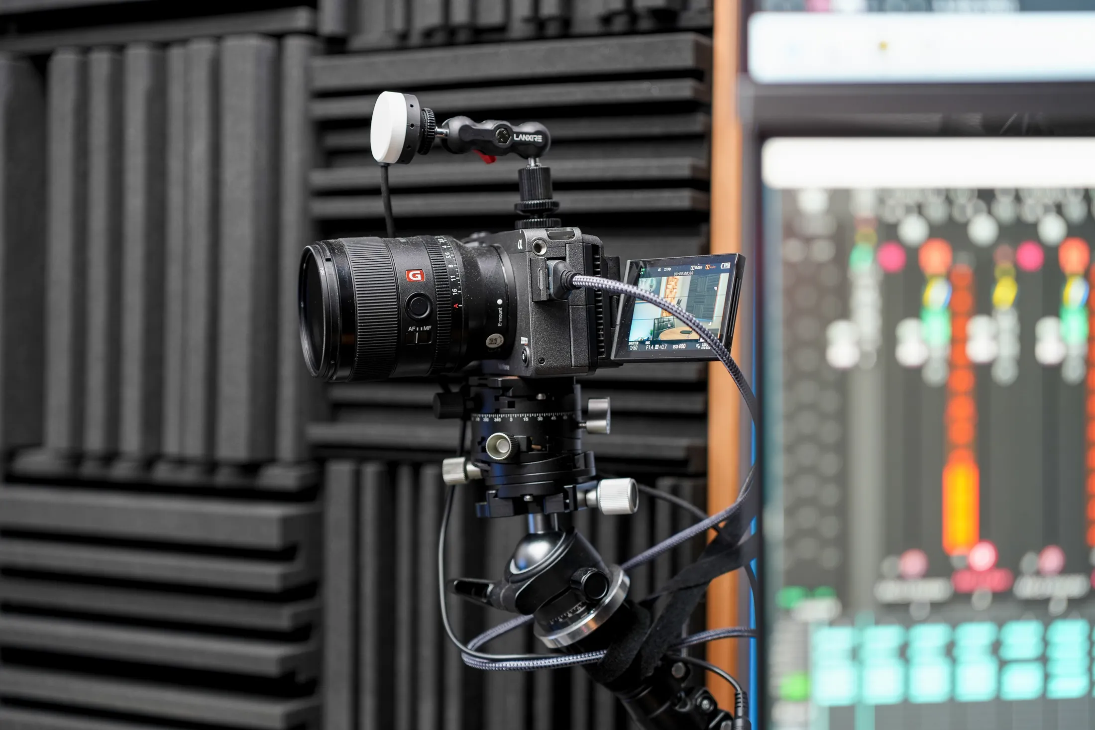 A Titan Podcasting studio camera prepared beside the live audio and switching monitors