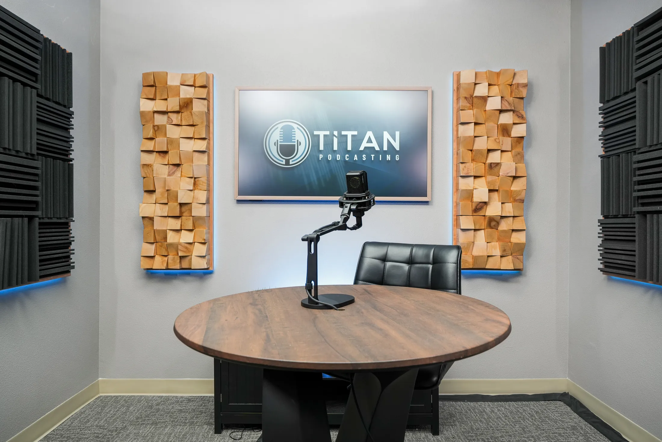 Prepared Titan Podcasting recording table with microphone, acoustic treatment, and on-set branding