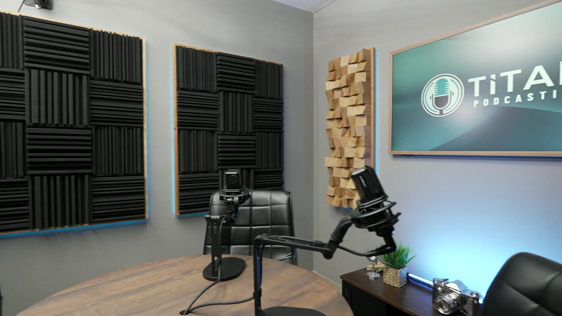 Wide view of the Titan Podcasting recording set with microphones, acoustic treatment, and on-set branding